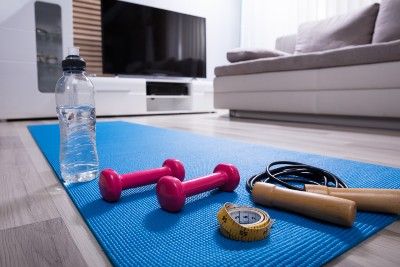 Exercise equipment sits on a yoga mat in a living room - Beachbody workout videos
