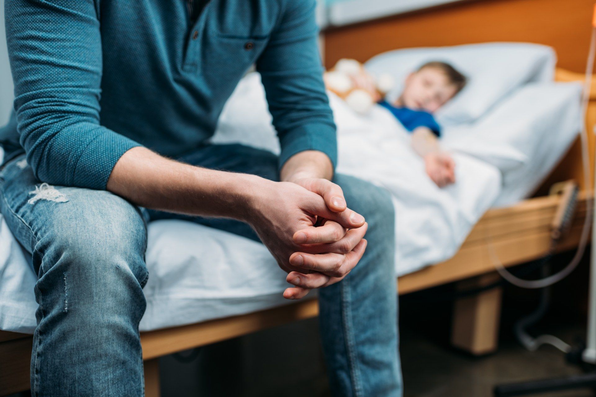 A man sits on a hospital bed where a little boy lies - coronavirus outbreak