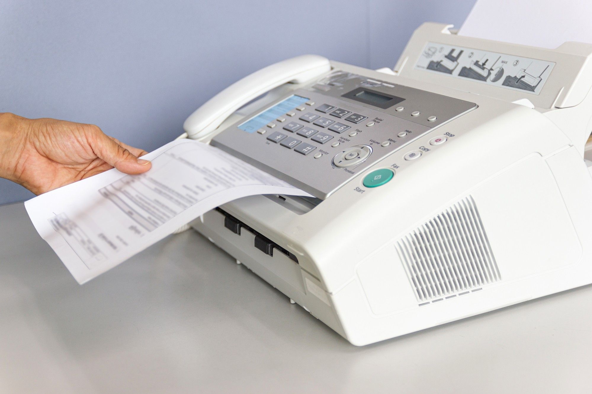 Fax machine with hand taking a fax