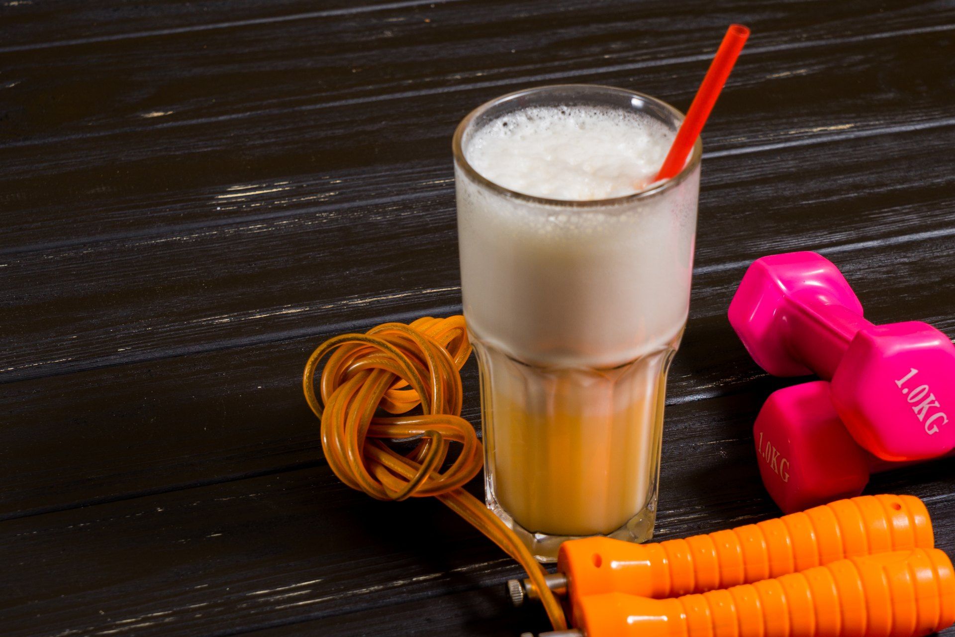 A fitness shake in a glass next to hand weights and other exercise equipment - Core Power protein shake