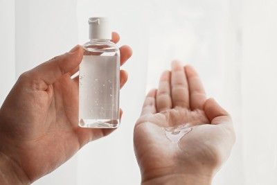 A person holds a bottle of hand sanitizer in one hand and a small amount of the gel in the other hand