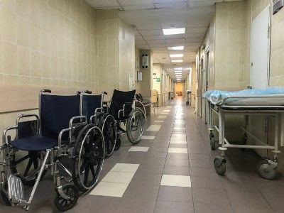 Wheelchairs and gurneys sit in a hospital hallway - nursing homes