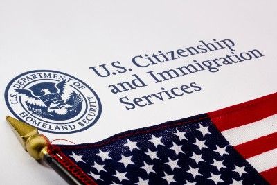 A U.S. flag lies on top of a U.S. Citizenship and Immigration Services paper - diversity visa lottery