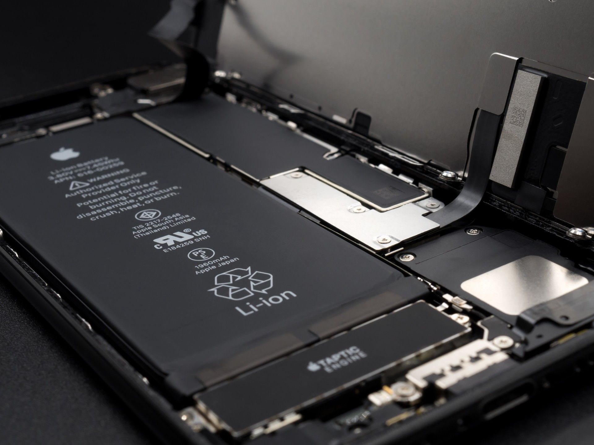 An iPhone lies open with the lithium-ion battery exposed