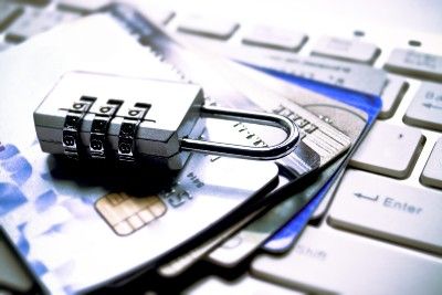 A closed padlock lies on top of a stack of fanned-out credit cards on a computer keyboard - data breach