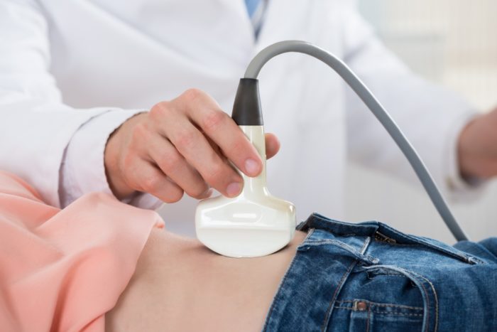 Doctor using ultrasound tool on pregnant woman.