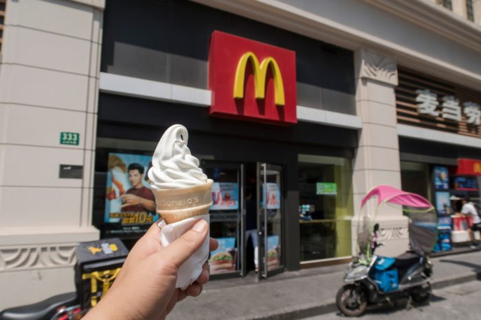 a person holding an vanilla ice cream cone outside of McDonald's