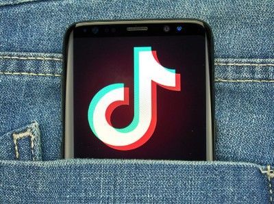 A smartphone showing a TikTok app screen sticks out from the back pocket of a pair of bluejeans - tiktok users