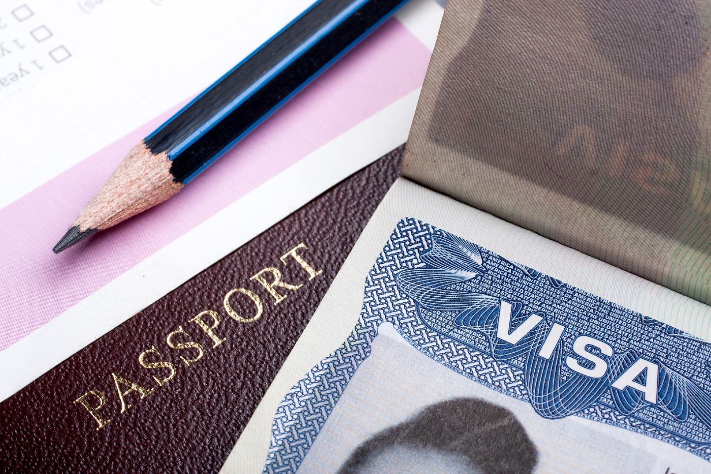 A pencil lies next to a passport and visa - diversity visa lottery