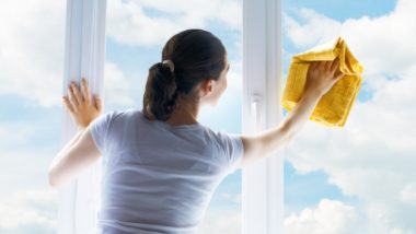 a woman cleaning her windows with Windex glass cleaner