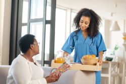 Nurse brings food tray to nursing home resident