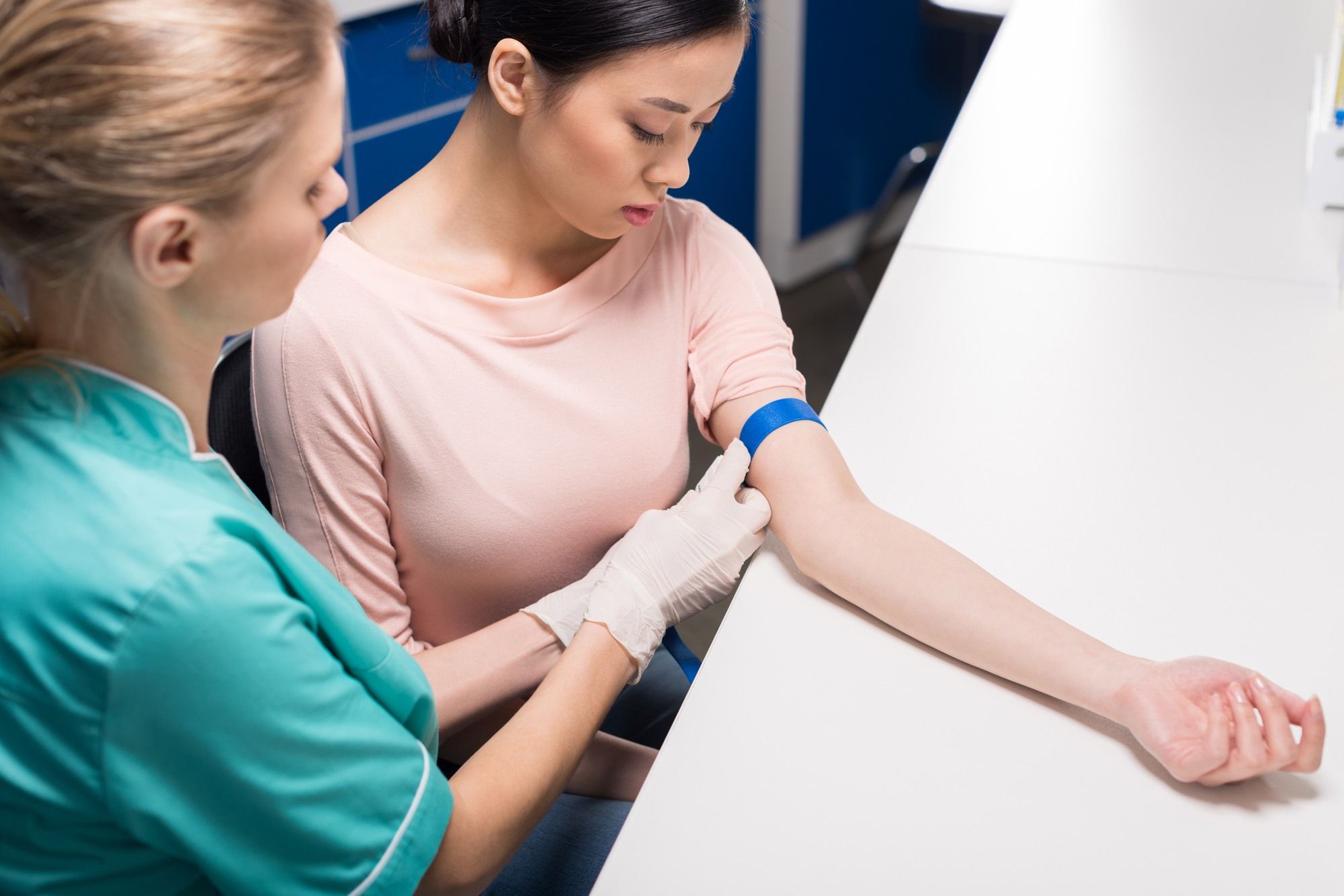 Female nurse preps female patient's arm for blood draw