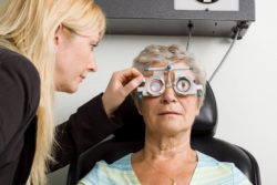 Female optometrist checks eyes of elderly female patient.