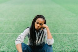 Unhappy young woman sits on sports field
