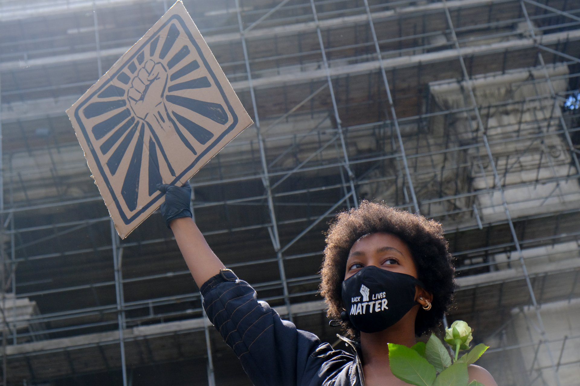 A female protester wears a "black lives matter" face mask and holds a fist sign - Black Lives Matter