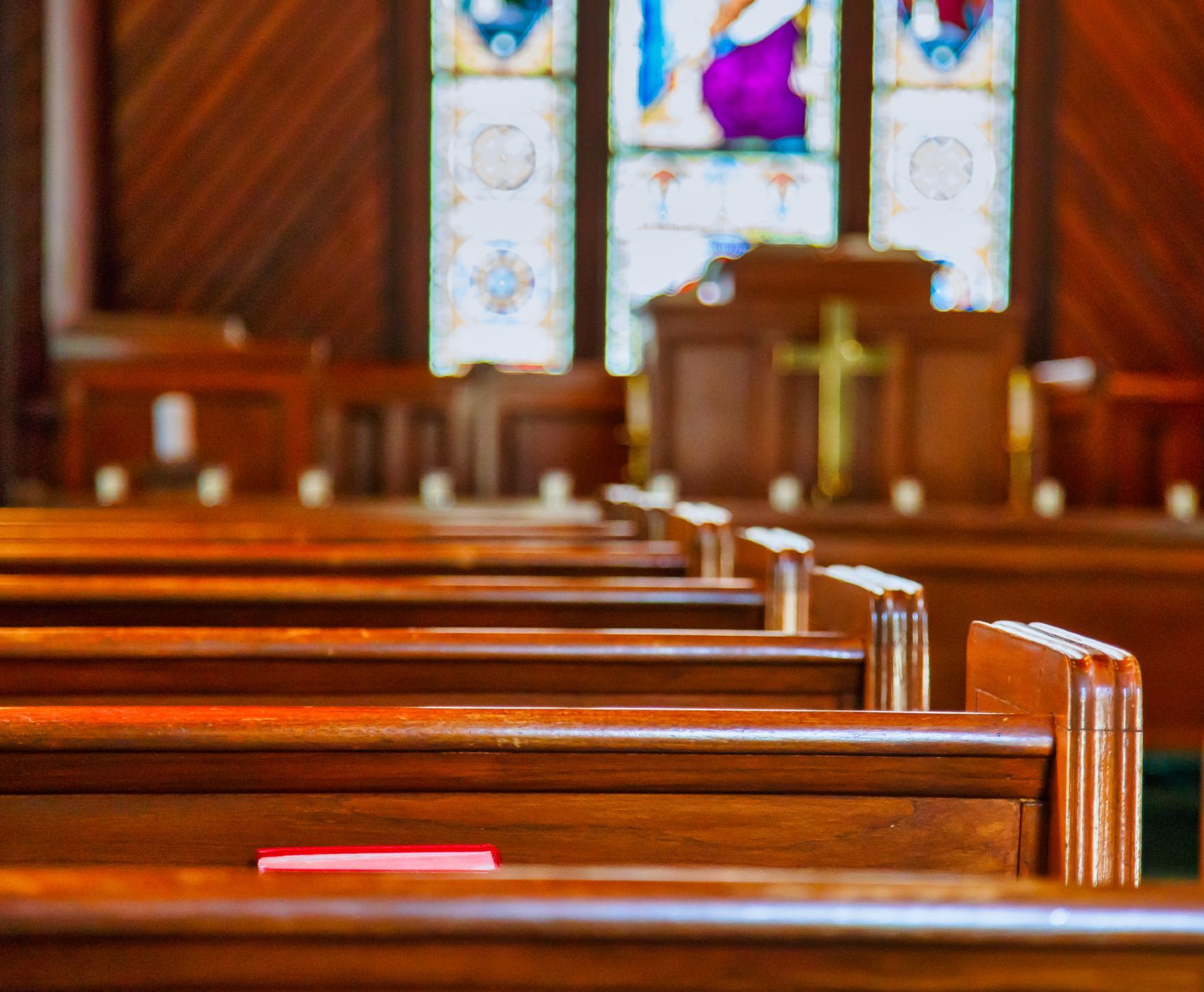 Empty wooden pews in a church with a stained glass window - colorado churches