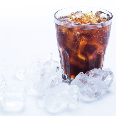 Cola in a glass with ice, surrounded by ice cubes - orange vanilla coca-cola