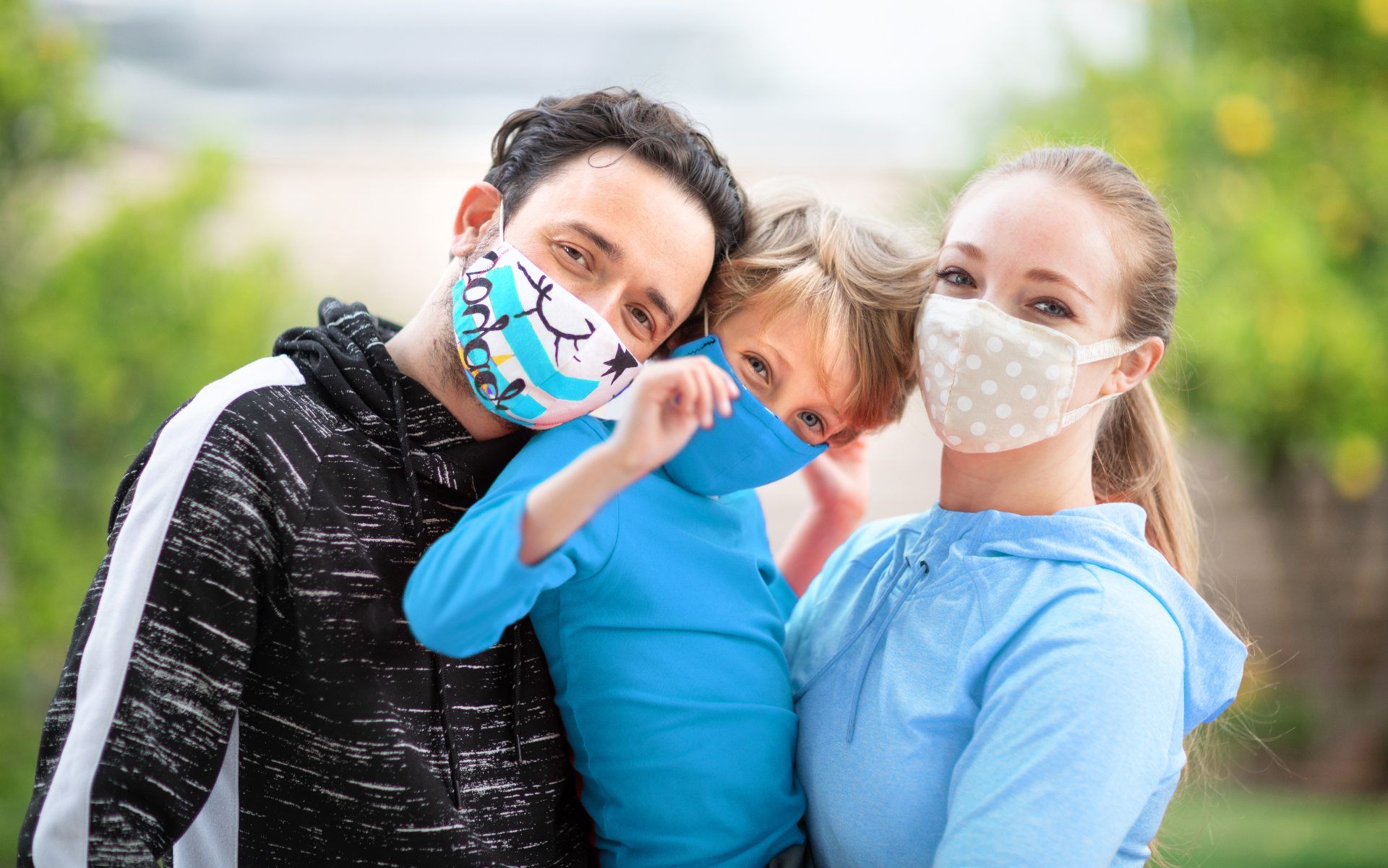 A man, woman and child wear face masks in various colors and patterns - sales tax