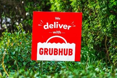 A red-and-white yard sign reads "We deliver with Grubhub" - grubhub partner