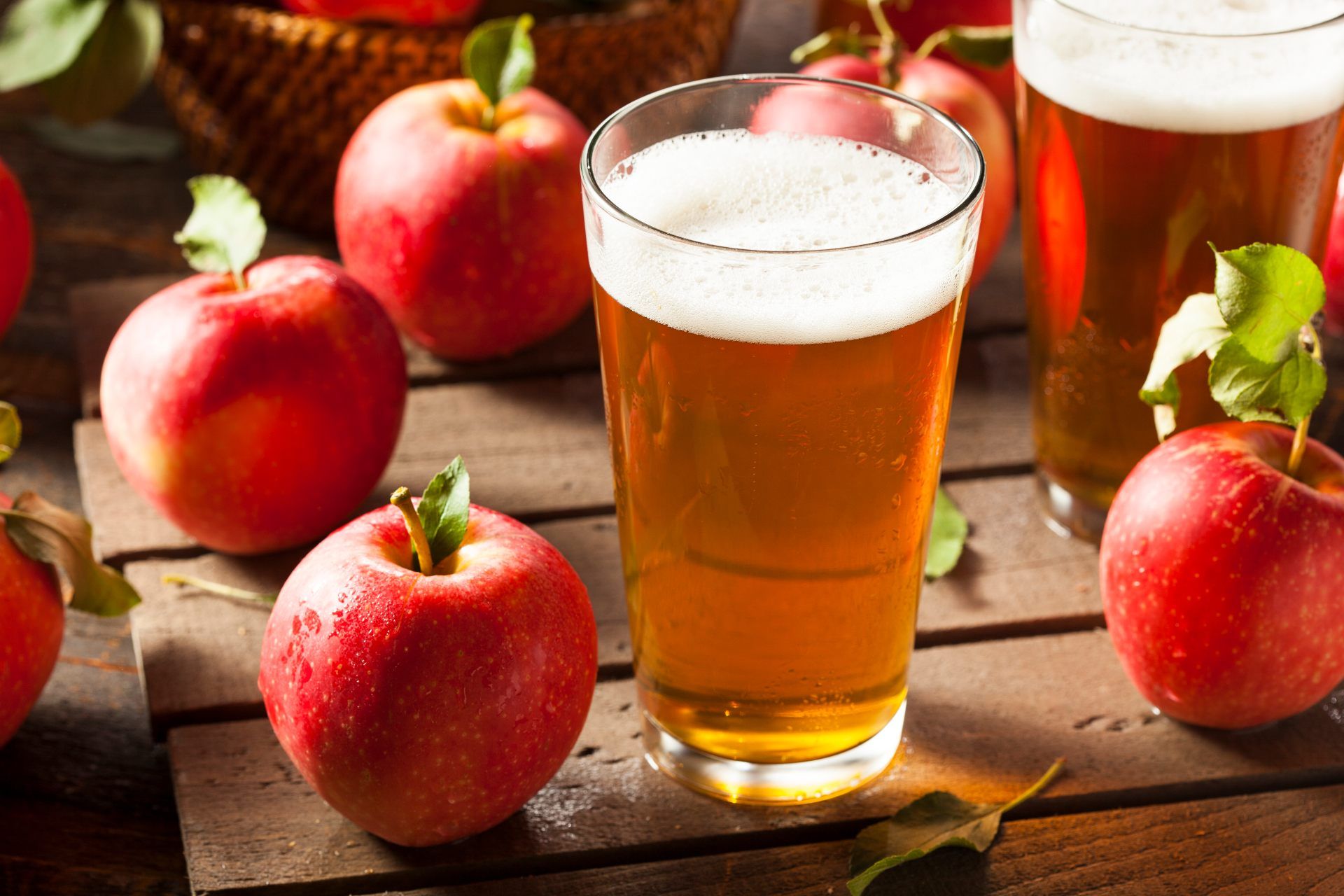 Hard apple cider in a glass surrounded by apples - hard cider