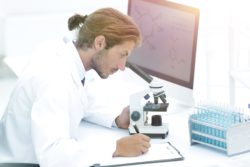 lab technician looking at sample under microscope