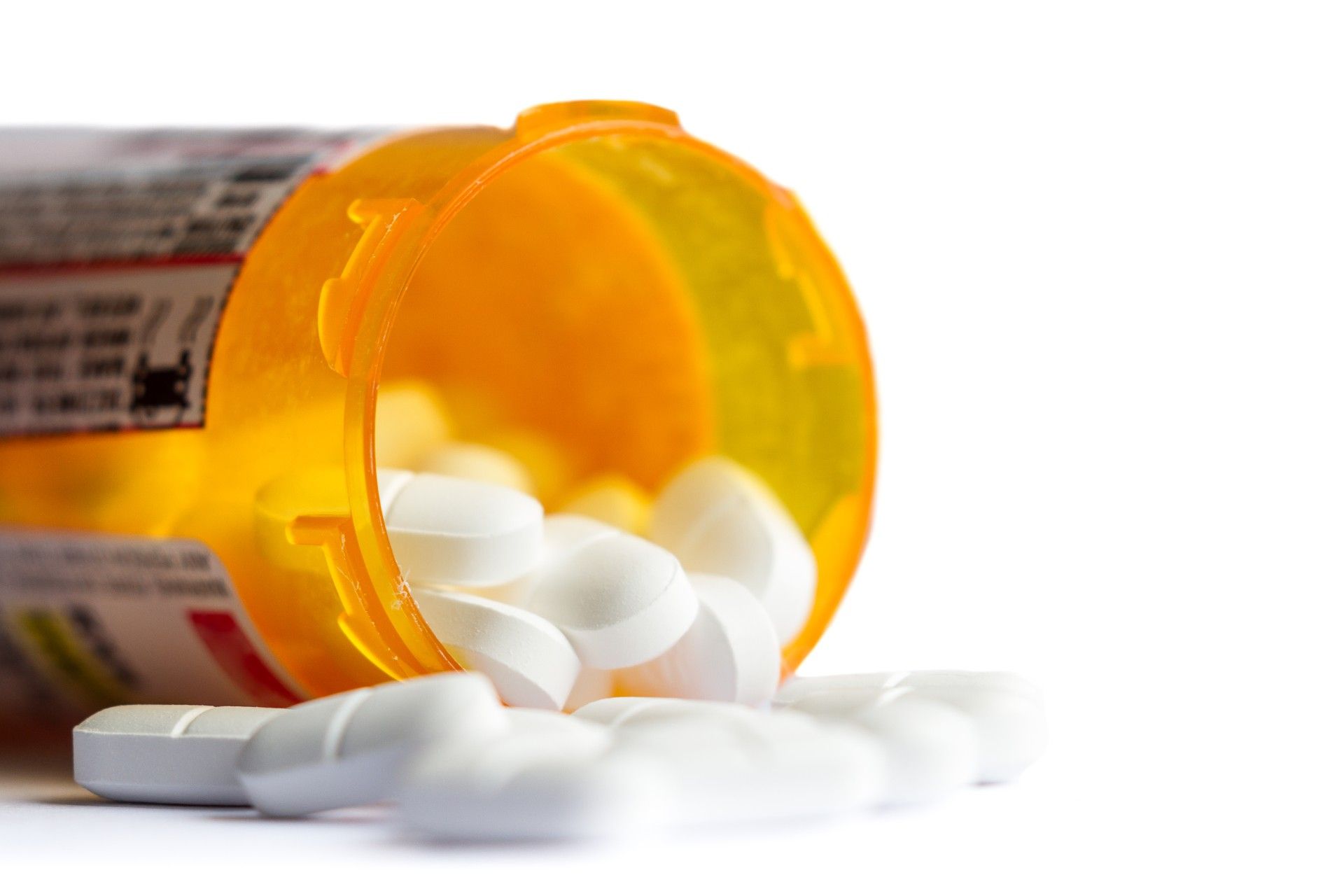 White pills spill out of overturned prescription bottle - opioid crisis