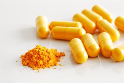Powdered turmeric next to turmeric pills - pain relief