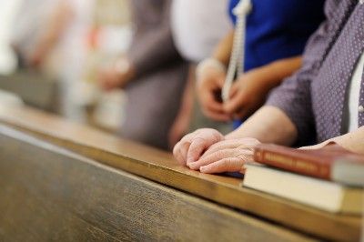A woman's hands on the pew in front of her in church - colorado churches