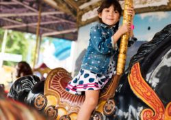 young female child riding merry-go-round