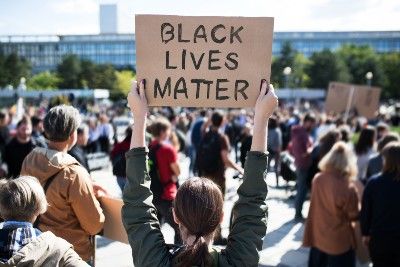 People attend a protest as a woman holds up a "Black Lives Matter" sign - police brutality
