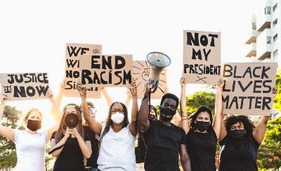 Racial justice protesters dress in black and white and hold signs - racial discrimination