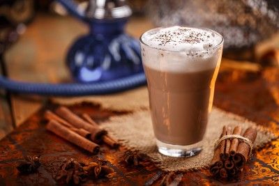 Chai latte in a glass, surrounded by spices - chai tea latte