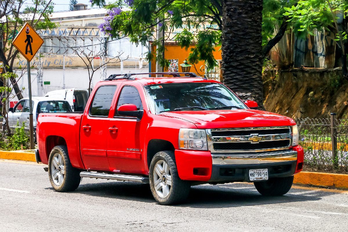 A red Chevrolet Silverado sits parked on a street - GM oil