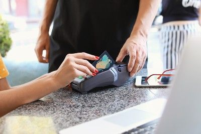 A woman slides a credit card through a credit-card reader - data breach