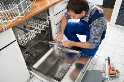 A repairman works on a dishwasher - dishwasher defect