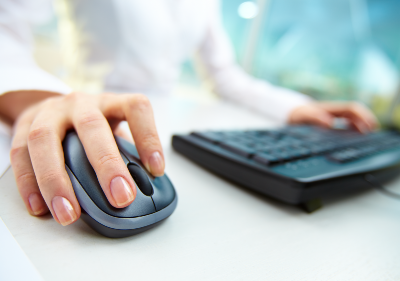 A woman's hand rests on a mouse near her keyboard - World of Warcraft website