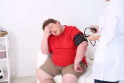 Overweight man has blood pressure checked by doctor
