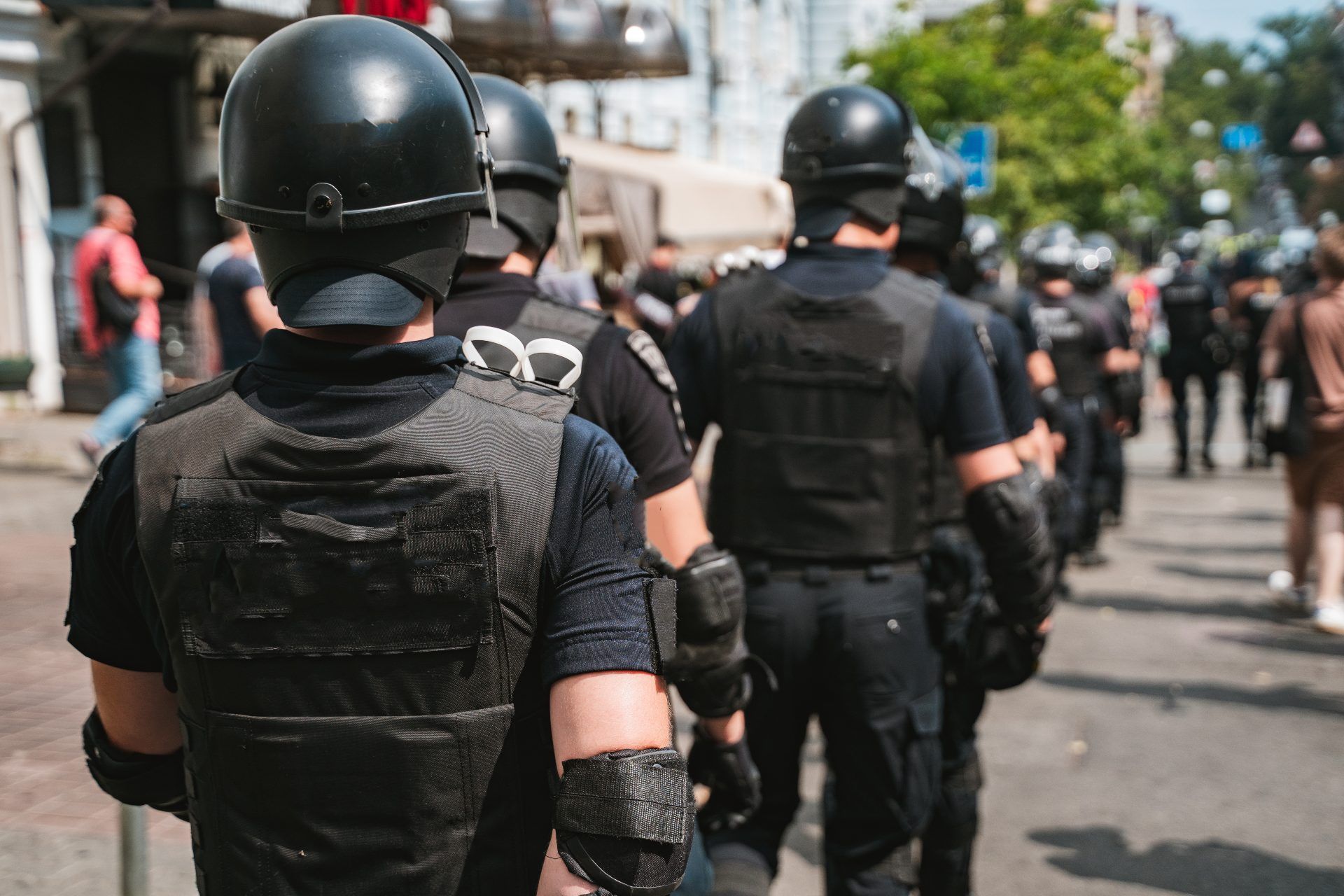 Police, seen from behind, wear riot gear to work during a protest - racial discrimination
