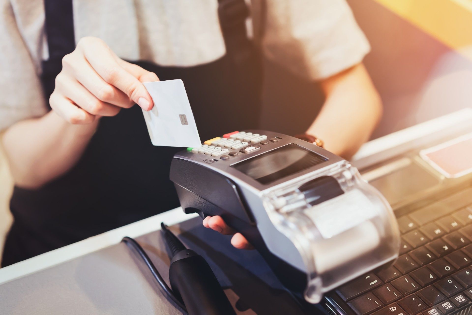 A person in an apron slides a credit card through a credit-card reader - data breach