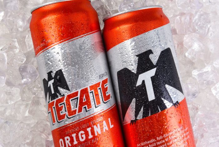 Two cans of Tecate beer on top of ice