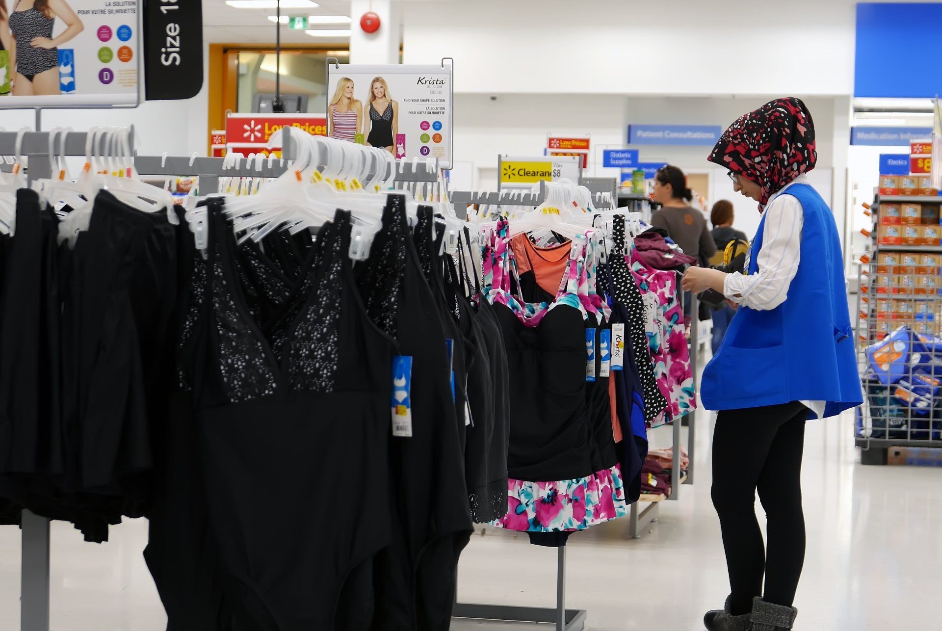A female Walmart employee checks tags on women's clothing - walmart return policy