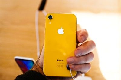 A customer looks at the back of a yellow iPhone XR
