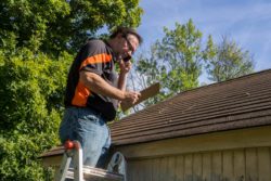 Male contractor inspects damaged roof