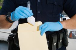 Officer collecting heroin as evidence regarding Oregon decriminalizing drugs 