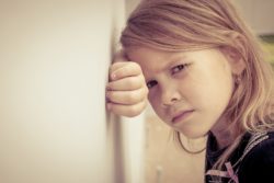 Sad little girl leans against wall