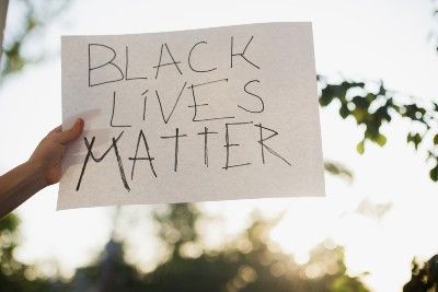 A person holds up a handwritten "black lives matter" sign - police violence