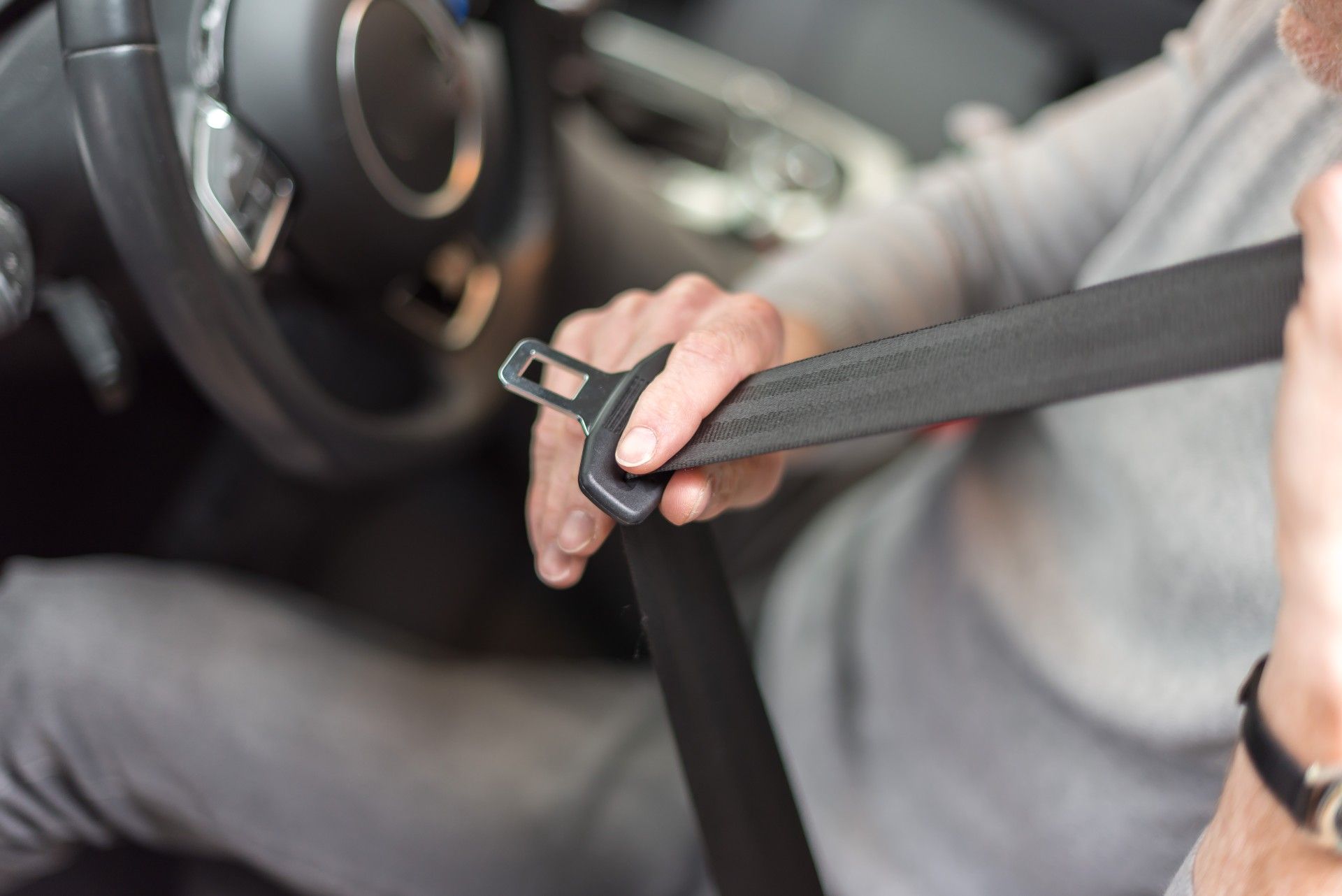A man in a grey shirt puts on a seat belt - seat belt recall