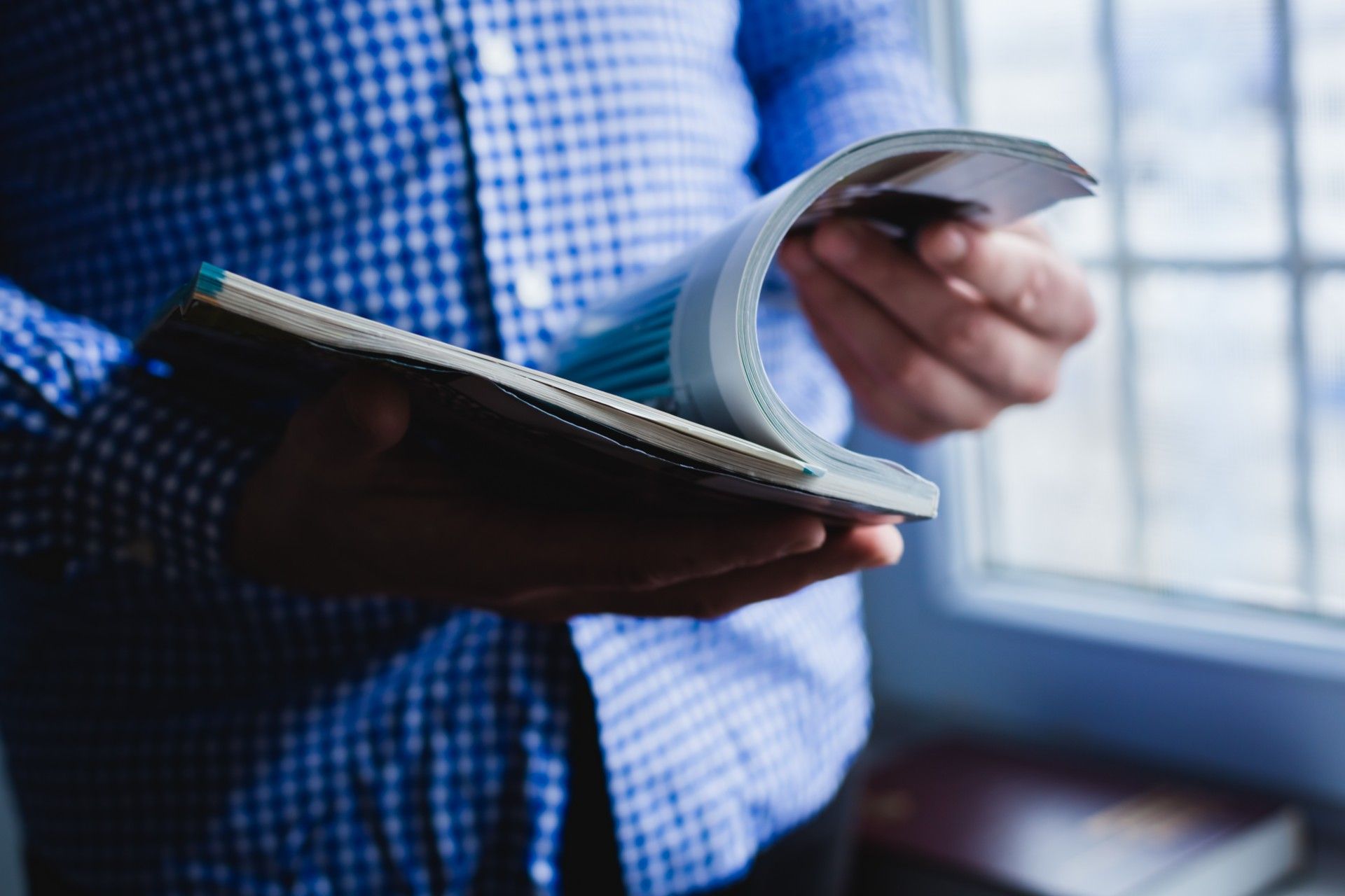 A man in a blue-checkered shirt reads a magazine - Autoweek magazine subscription