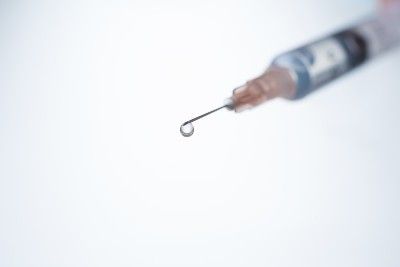 Medicine drips from the tip of a needle on a syringe - coronavirus vaccine