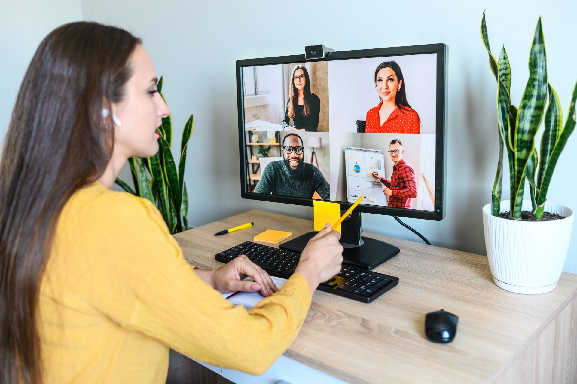 A woman in a yellow shirt participates in a video conference via computer - Zoom privacy